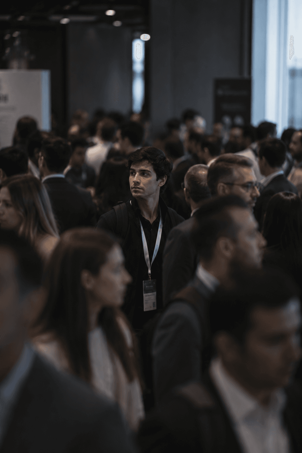 One attendee standing alone in a crowded conference room full of badges